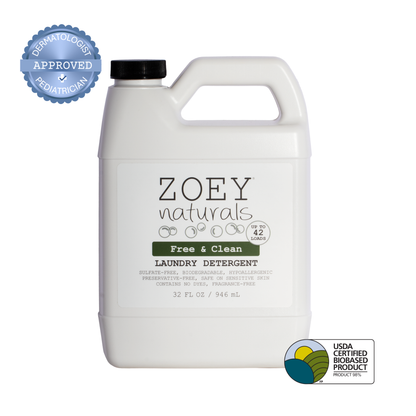 A 32 fl oz white plastic bottle of Zoey Naturals Free & Clean Laundry Detergent with a black cap, shown on a white background with a blue dermatologist/approval badge on the top left and a USDA Certified Biobased Product seal on the bottom right.